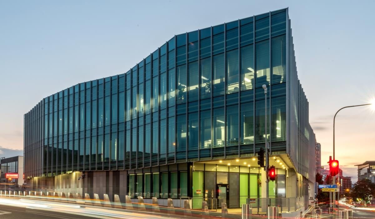 Multi-storey commercial building with a faceted glazed curtain-wall facade, photographed at dusk