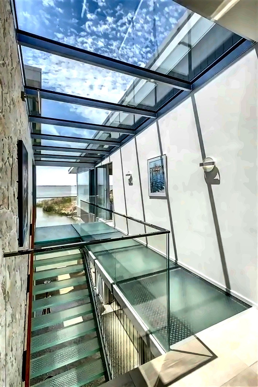 Glazed internal walkway and stair with a glass floor and balustrade beneath a fully glazed roof