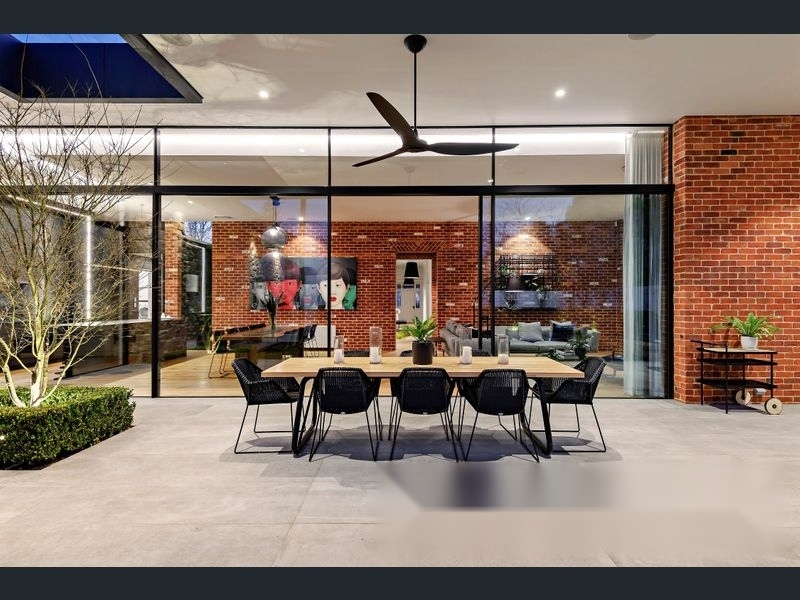 Norwood 18 Project — Schüco sliding doors open to brick feature wall dining area at dusk
