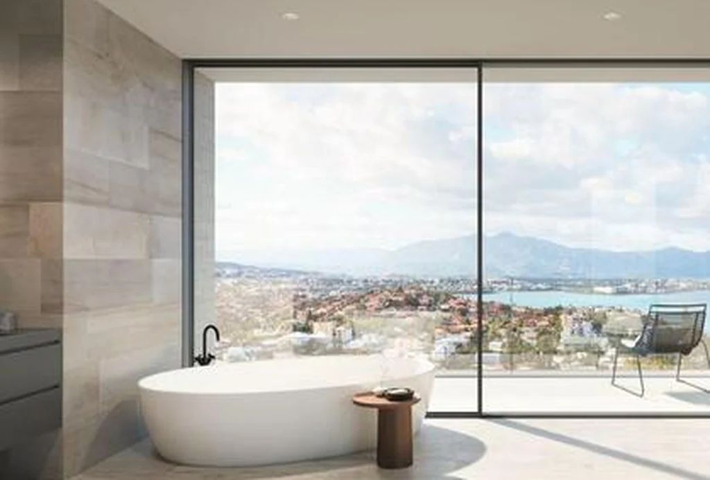 Bathroom behind a Schüco AS PD 75.HI panoramic sliding wall with a coastal view