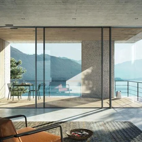 Living space behind a Schüco FWS 35 PD façade opening to a lake and mountain view