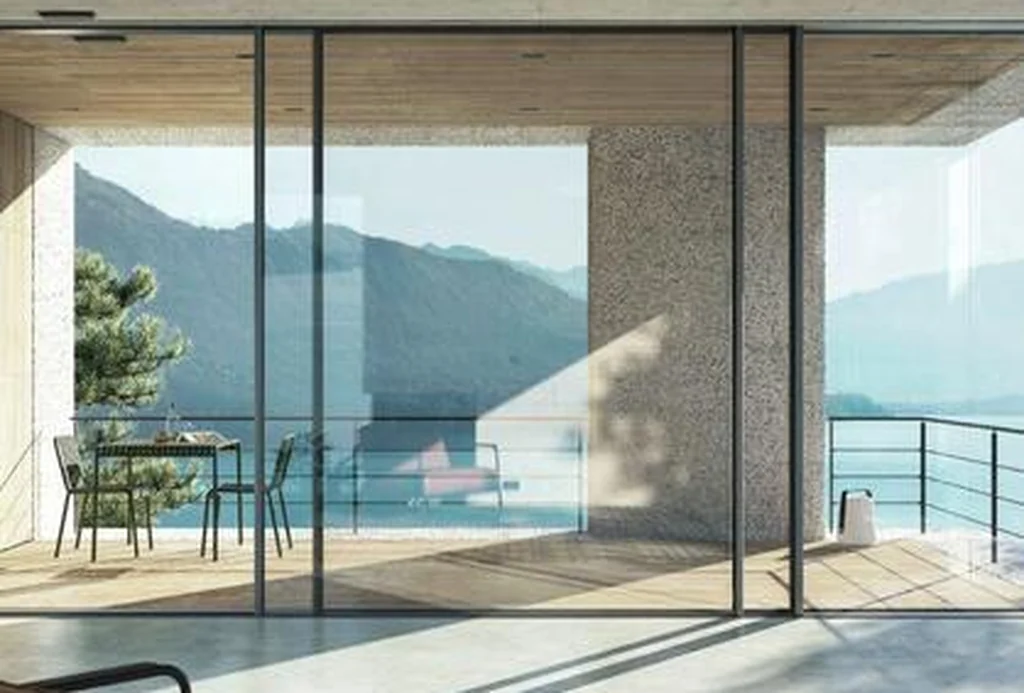 Living space behind a Schüco FWS 35 PD façade opening to a lake and mountain view